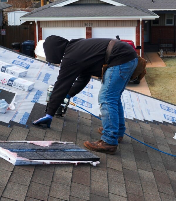 Man installing new asphalt shingles to roof of home